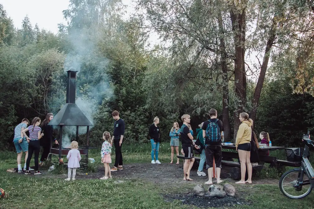Lõkkeplats metsa ääres, inimesed ümber
